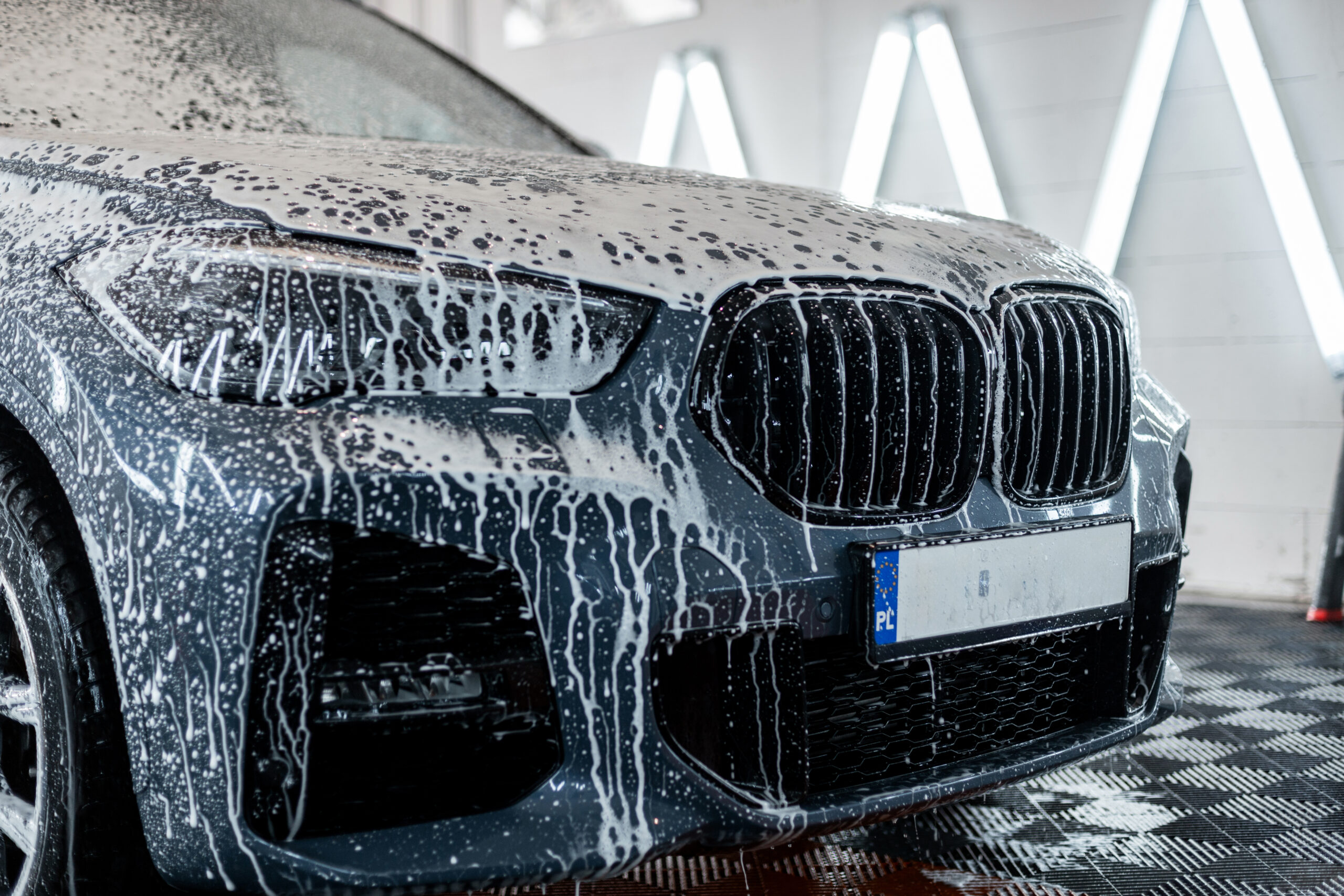 Car is washed at a professional car wash. Man washes a car with foam. Detailing