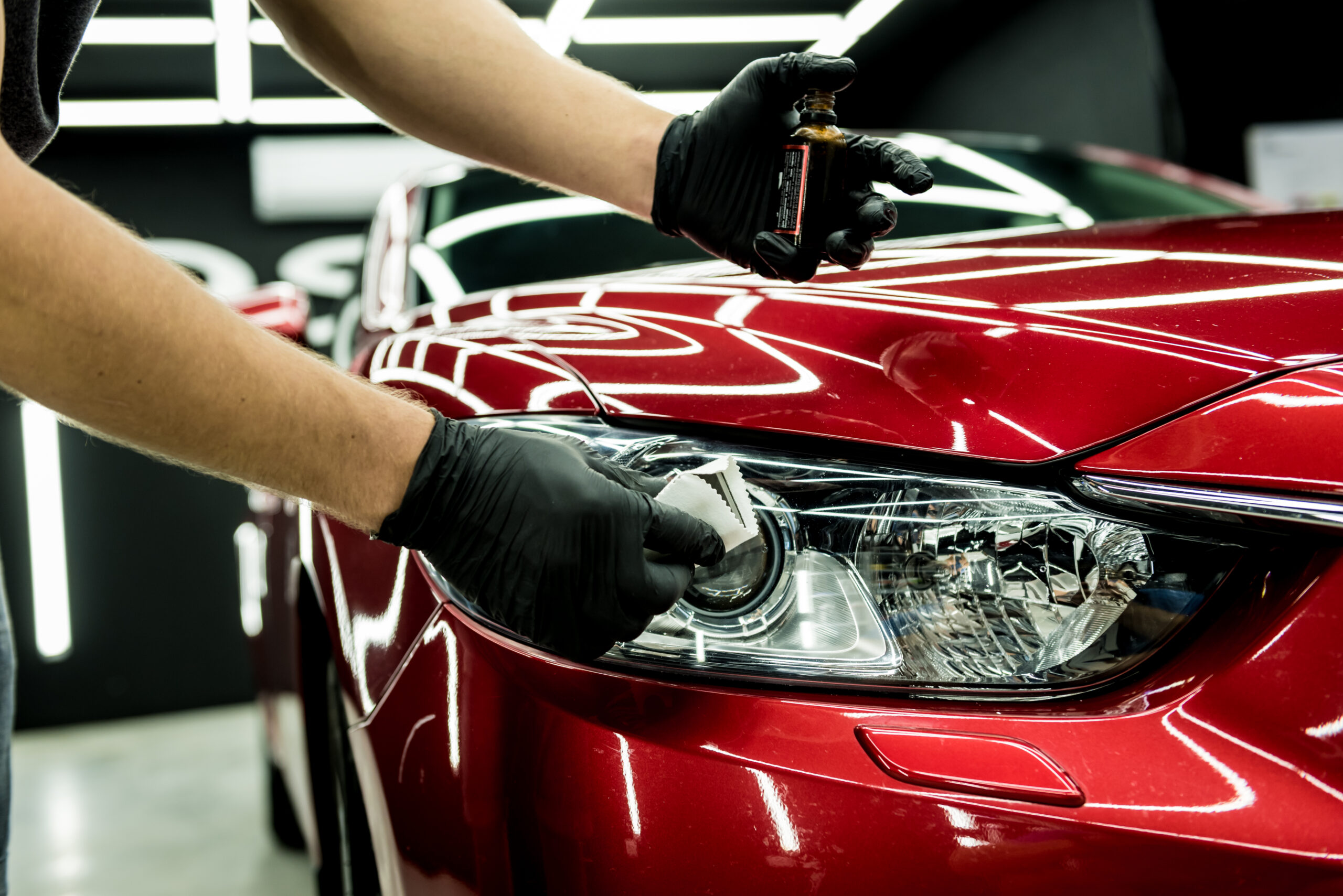 Car service worker applying nano coating on a car detail